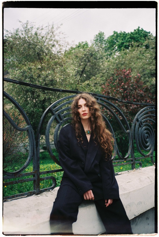 A girl with curly hair sitting in a garden