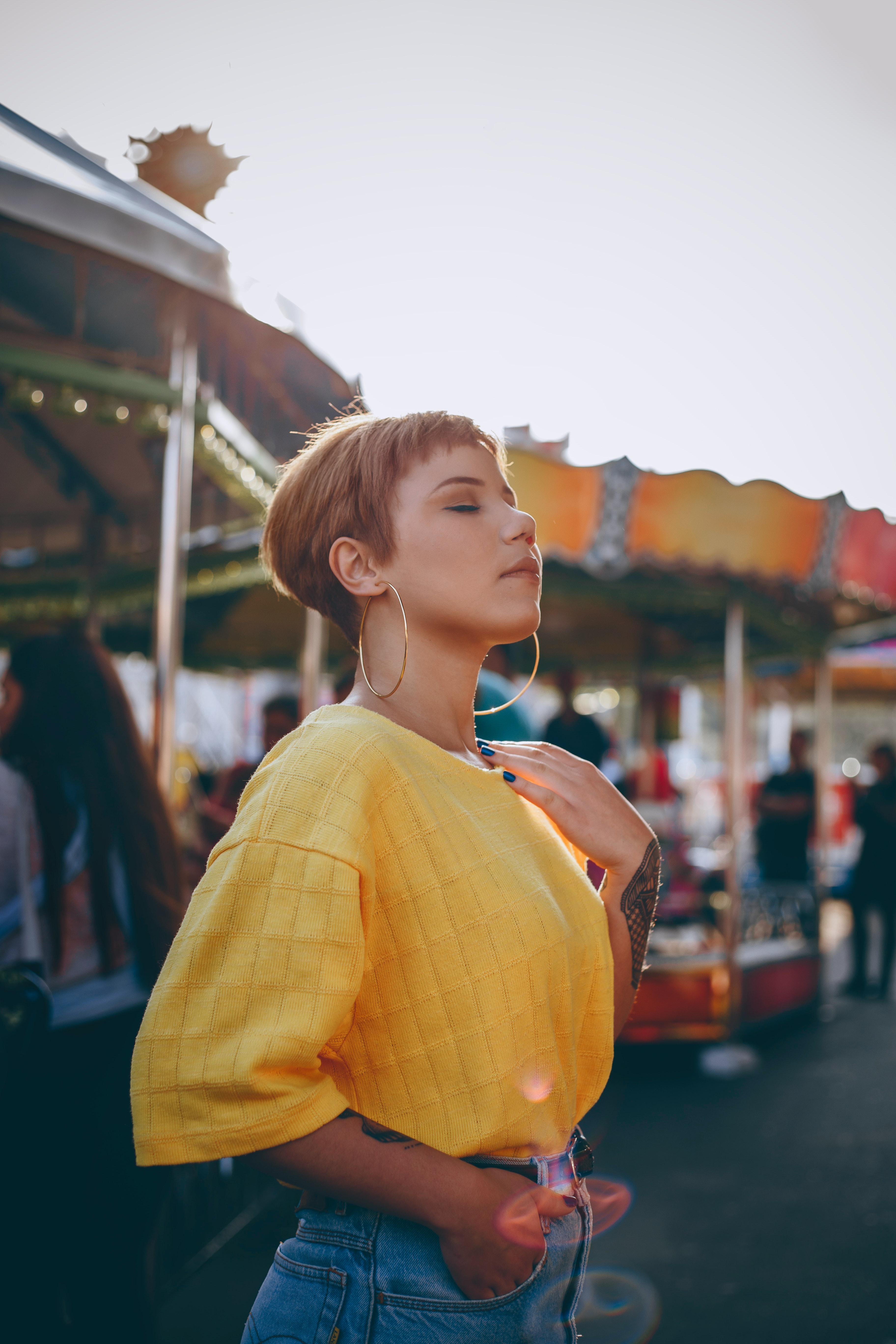 A lady in a park wearing yellow shirt and light blue jeans